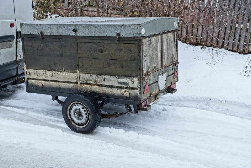 Old gray wooden trailer with black wheels on white snow on the road. Old gray closed wooden trailer with black wheels on white snow on the road stock photos Old gray wooden trailer with black wheels on white snow on the road. Old gray closed wooden trailer with black wheels on white snow on the road stock photos