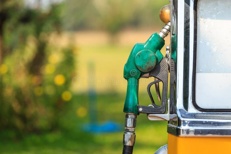 Old of green fuel nozzle in gas station on green blur