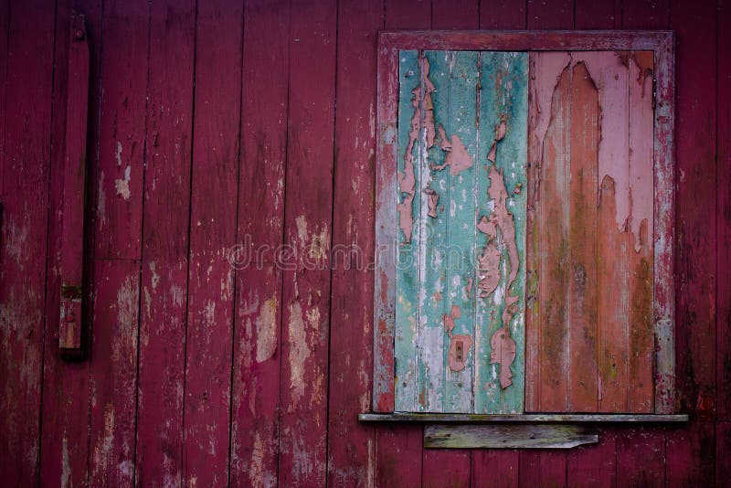 Old grunge and weathered home facade with green window and red wall planks texture background