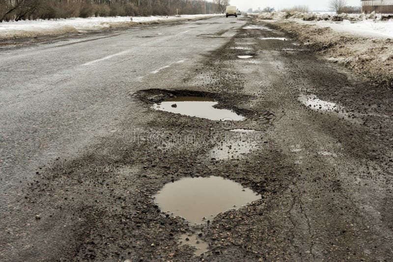 Old highway with holes and snow. Landscape road potholes