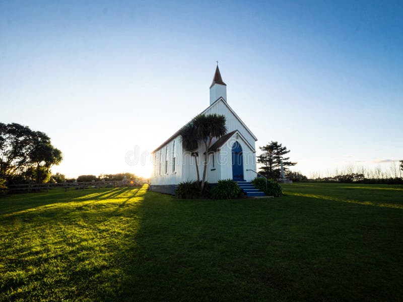 Old historic 19th century white presbyterian Awhitu Central Church with green grass during sunset on Manukau Heads Peninsula Auckland North Island New Zealand. Old historic 19th century white presbyterian Awhitu Central Church with green grass during sunset on Manukau Heads Peninsula Auckland North Island New Zealand