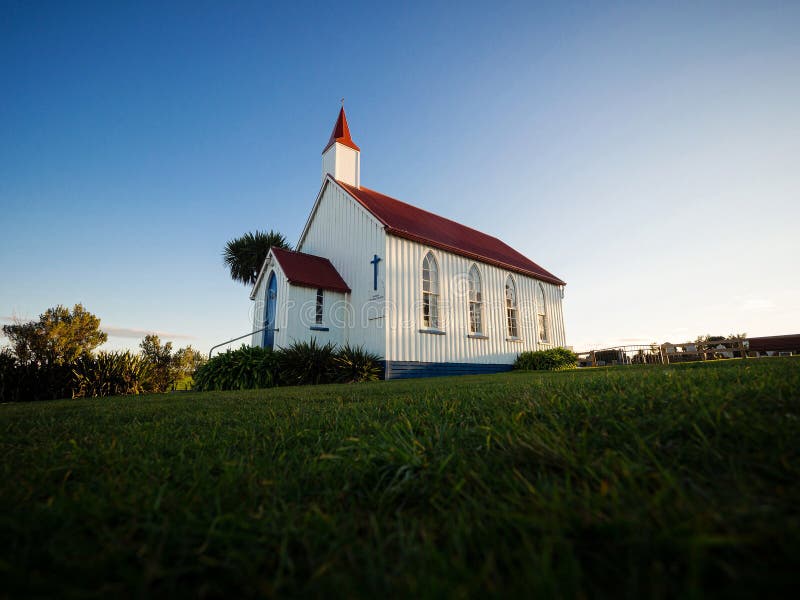 Old historic 19th century white presbyterian Awhitu Central Church with green grass during sunset on Manukau Heads Peninsula Auckland North Island New Zealand. Old historic 19th century white presbyterian Awhitu Central Church with green grass during sunset on Manukau Heads Peninsula Auckland North Island New Zealand