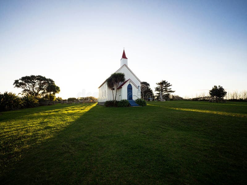 Old historic 19th century white presbyterian Awhitu Central Church with green grass during sunset on Manukau Heads Peninsula Auckland North Island New Zealand. Old historic 19th century white presbyterian Awhitu Central Church with green grass during sunset on Manukau Heads Peninsula Auckland North Island New Zealand