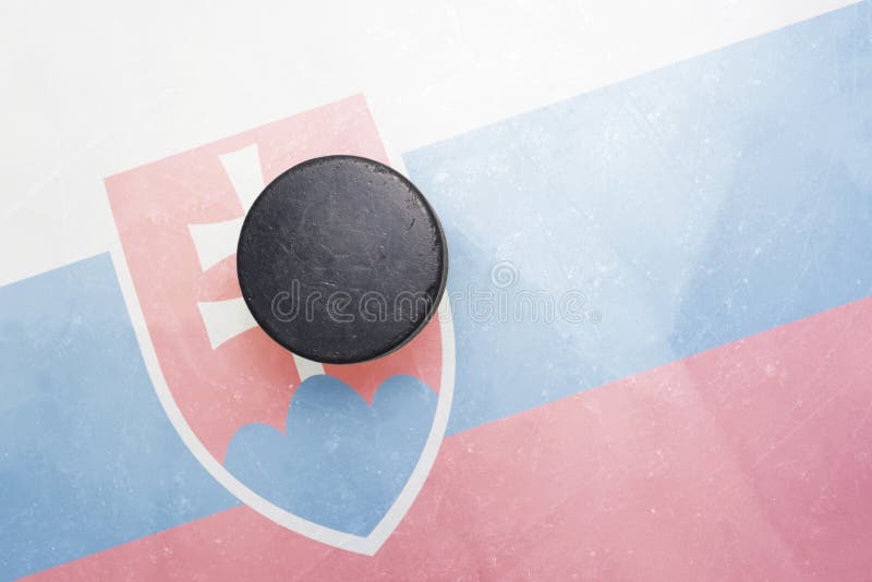 Starý hokejový puk je na ľade so slovenskou vlajkou