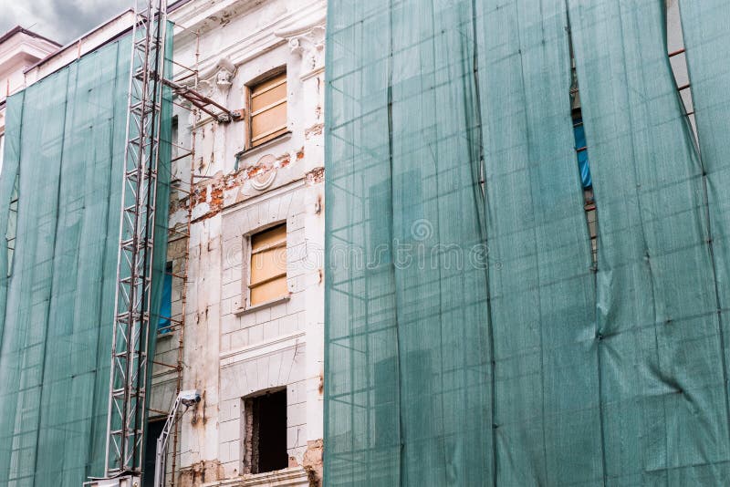 Old house under renovation wrapped in a green net for safety