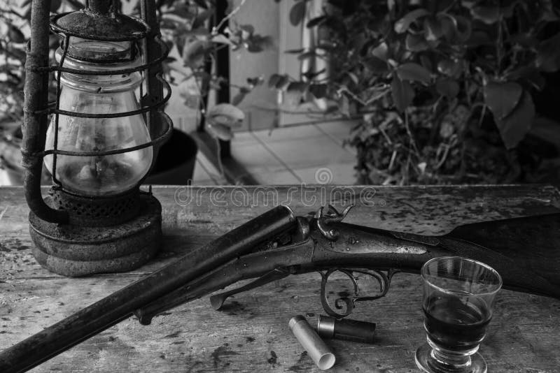 Hunting composition with old rifle, lamp and glass of wine