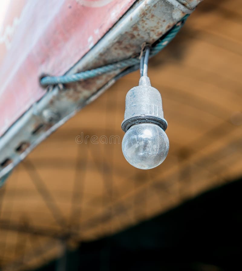 Old Incandescent Light Bulb Hanging on Black Electric Wire Stock Photo