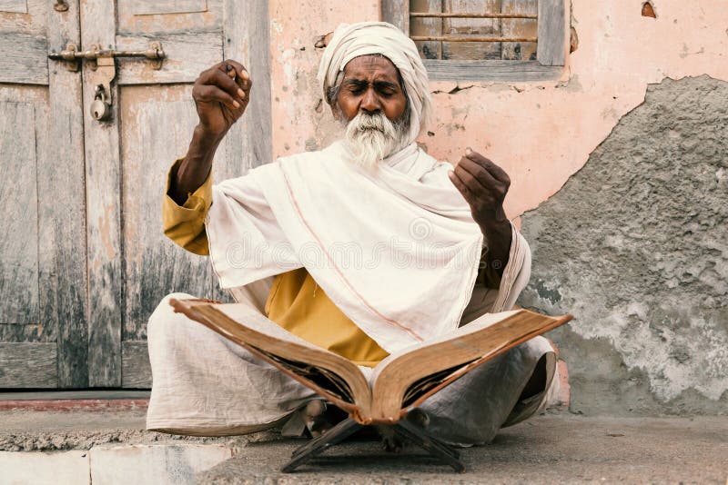 Old indian sadhu reading scriptures.