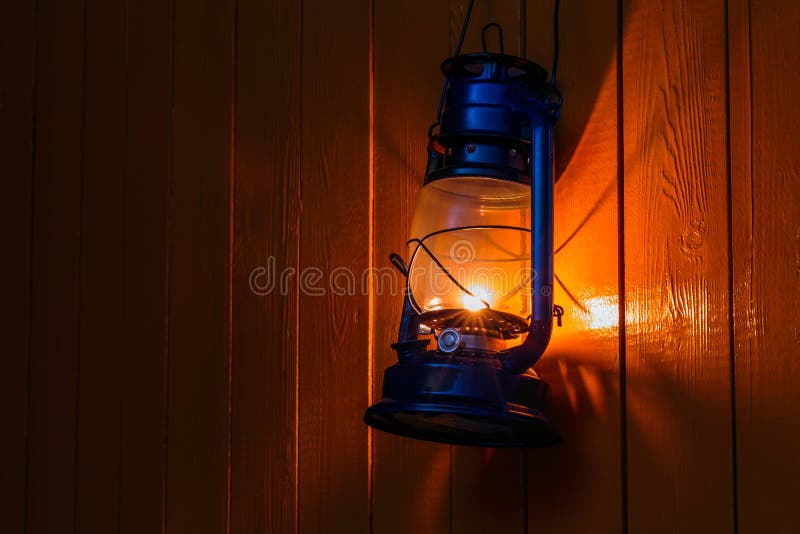 Old kerosene lantern hanging on the yellow wooden wall