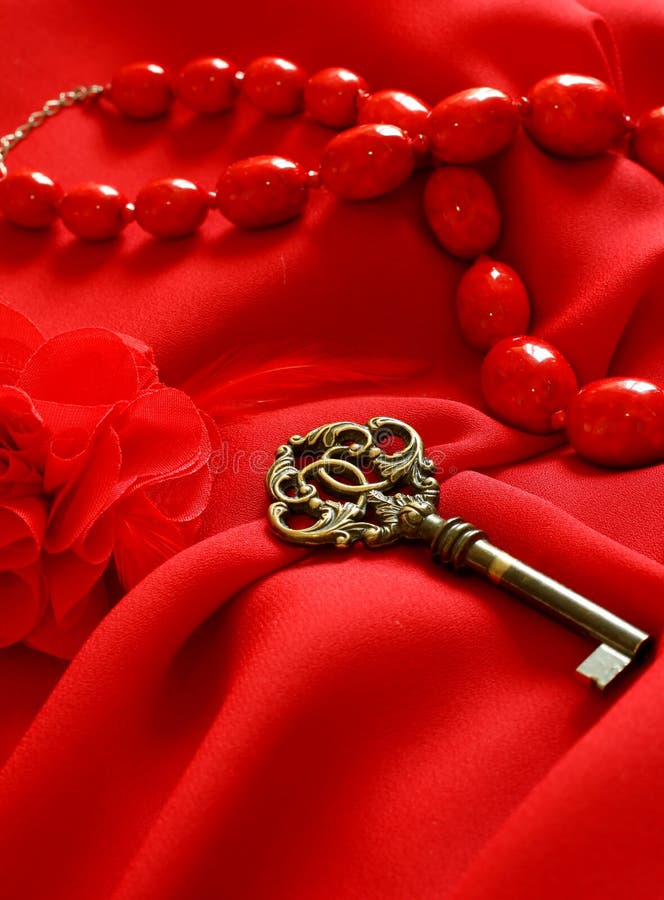 Old key and woman beads on red silk