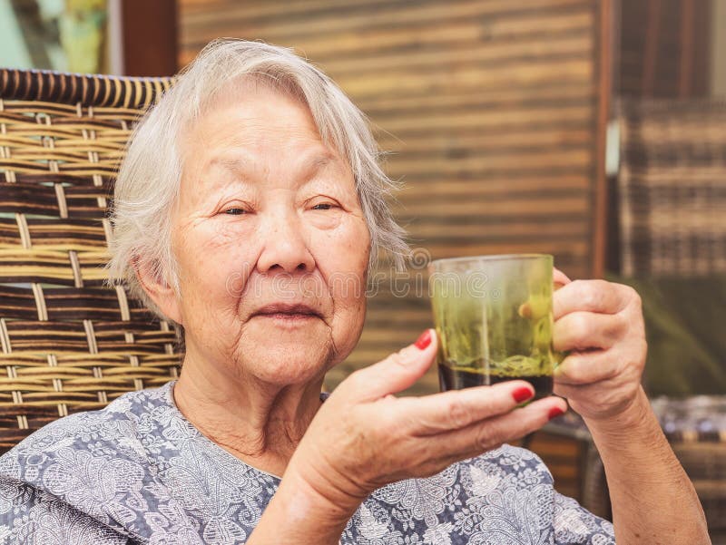 Old lady seated comfortably at home holding a cup of black coffee. stock photos Old lady seated comfortably at home holding a cup of black coffee. stock photos