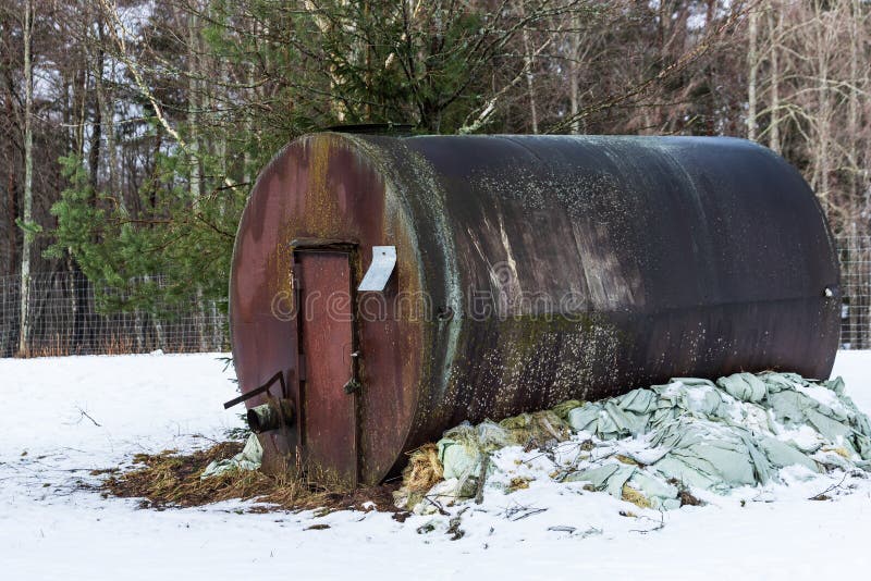 An old, large, rusty barrel with a locked door on a winter day stock photography