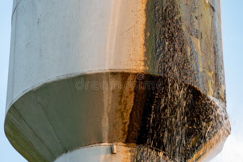 An Old Leaky Water Tower. Water Flows from a Large Iron Barrel Stock