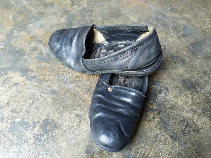 Broken old leather shoes isolated on cement floor