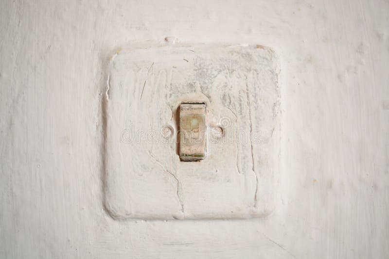 Old light switch on a white old wall on a traditional house in Romania