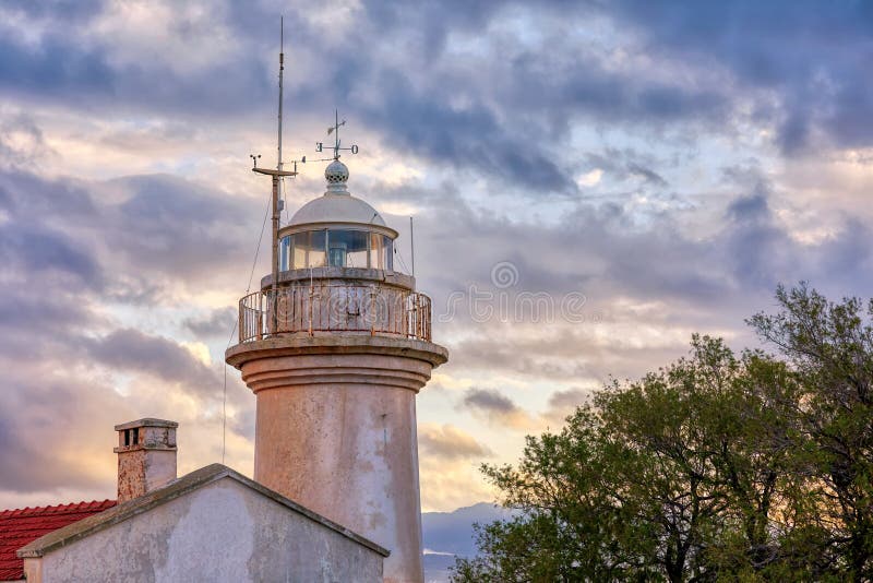 Old lighthouse tower against a moody cloudy sky at sundown