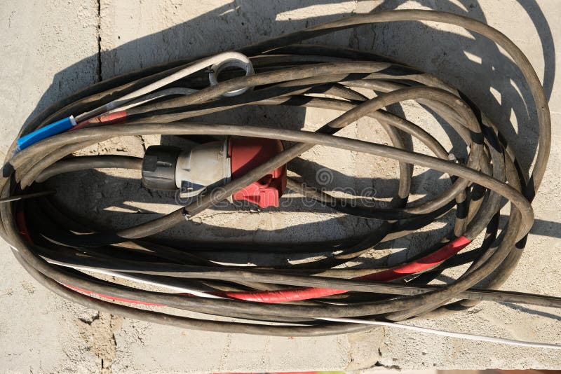 Old Long Coiled Electrical Cable with a Socket Hanging from a Nail