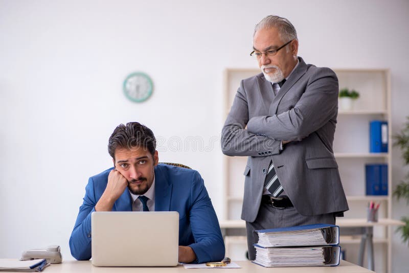 Old Male Boss and Young Male Employee Working in the Office Stock Photo