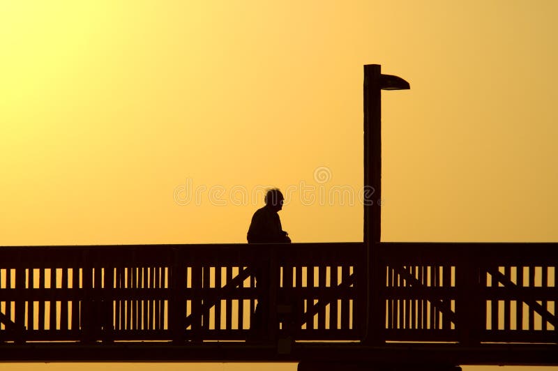Elderly man walks boardwalk alone at days end. Boardwalk rail stock images, royalty-free photos and pictures