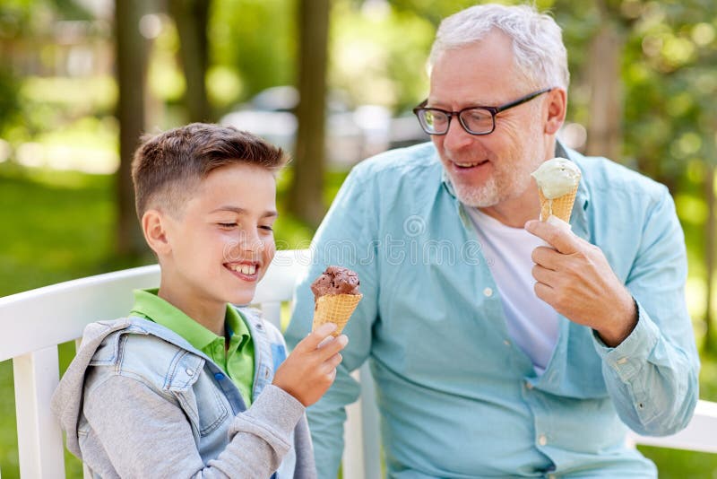 Old man and boy eating ice cream at summer park