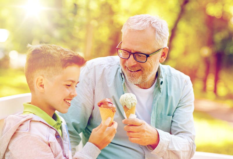 Old man and boy eating ice cream at summer park