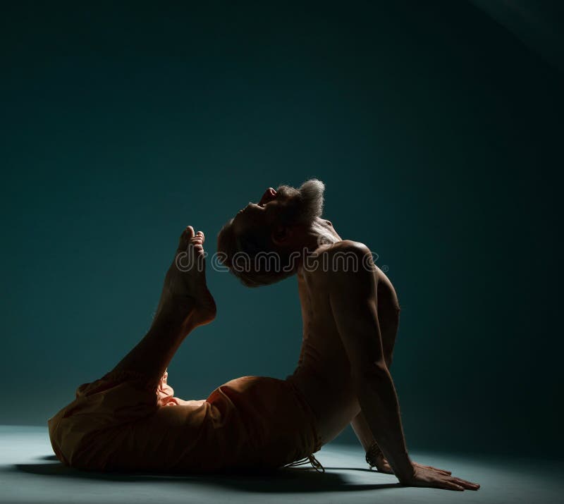 Old man with grey beard doing yoga, pilates, fitness training, stretching exercise, asana or balance workout on floor