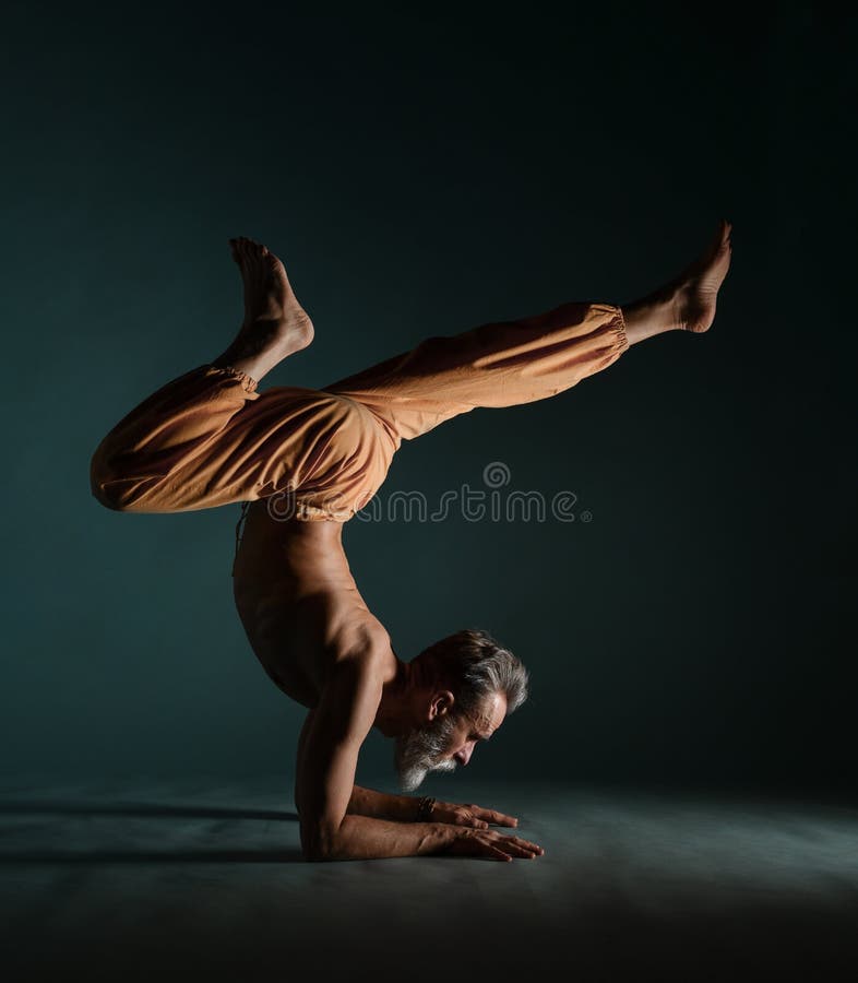 Old man with grey beard doing yoga, pilates, fitness training, stretching exercise, asana or balance workout on floor