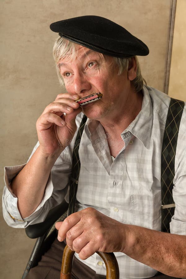 Elderly man playing his harmonica holding his cane. Elderly man playing his harmonica holding his cane