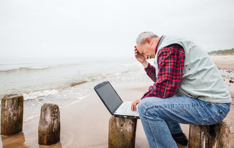 Old man with notebook on beach