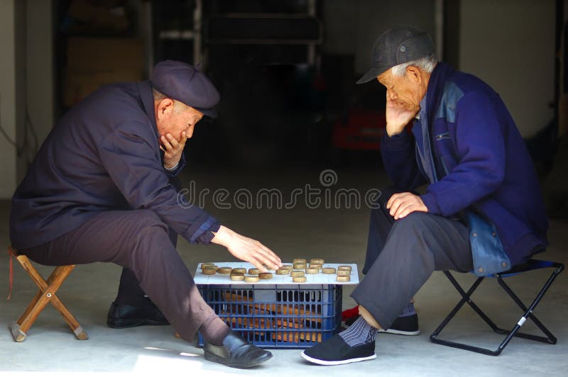 Due vecchi uomo Cinese di giocare a scacchi cinesi vicino alla porta che aveva aperto all'esterno in magazzino.