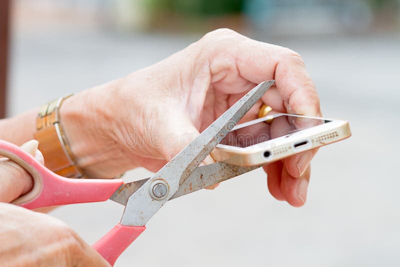 The Old Man's Hand Holding Scissors And Cut Mobile Phone Stock Image