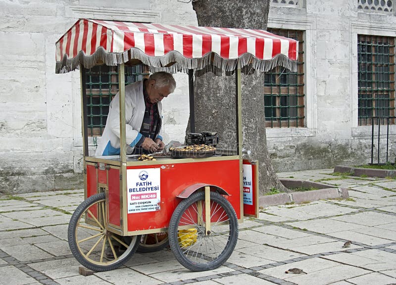 Old man selling baked sweet chestnuts, raw