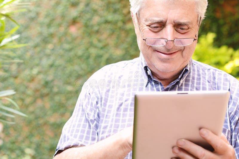 Old man using digital tablet. stock image