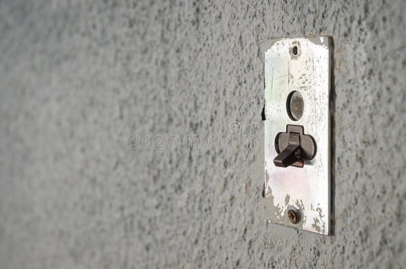 An old lightning electrical switch on gray wall. Metal base with plastic switch. Clean composition with copy space for text, words, etc. nobody in picture. empty. An old lightning electrical switch on gray wall. Metal base with plastic switch. Clean composition with copy space for text, words, etc. nobody in picture. empty.