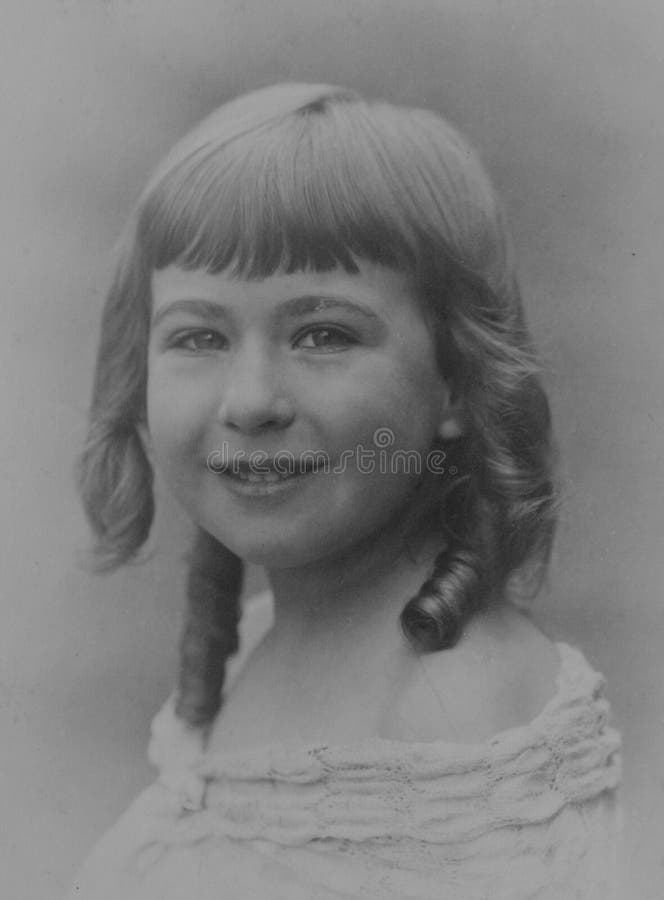 Old monochrome photograph of a young girl with ringlets, dating to the 1930s, Edwardian era. Vintage monochrome studio photograph of a pretty Caucasian young