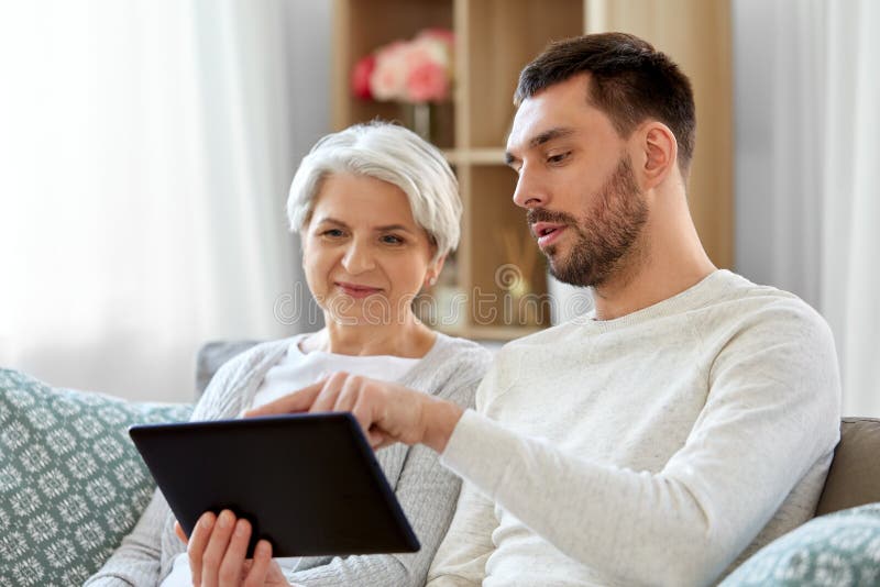 Old mother and adult son with tablet pc at home