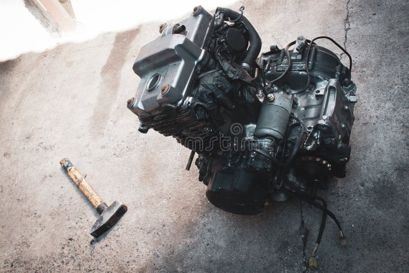 Old motorcycle engine with hammer in workshop