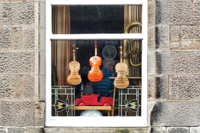 Old musical instruments in the window of a second-hand and antiques shop in the village of Falkland in Scotland. Falkland, UK - March 23, 2019: Old musical stock photography Old musical instruments in the window of a second-hand and antiques shop in the village of Falkland in Scotland. Falkland, UK - March 23, 2019: Old musical stock photography