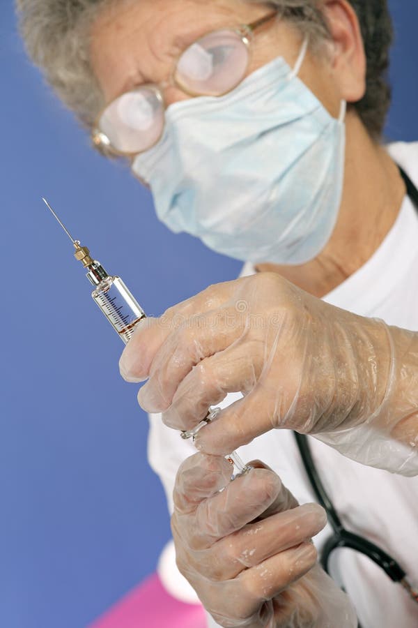 Old nurse with protective mask and gloves prepares injection of vaccine or medicine for disease prevention with glass syringe and stock photo Old nurse with protective mask and gloves prepares injection of vaccine or medicine for disease prevention with glass syringe and stock photo