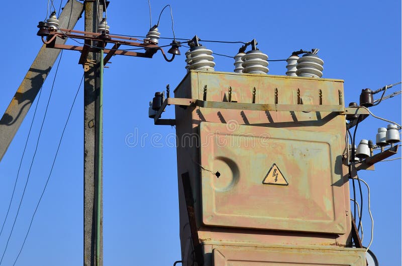 Old and obsolete electrical transformer against the background of a cloudless blue sky. Device for distribution of supply of high