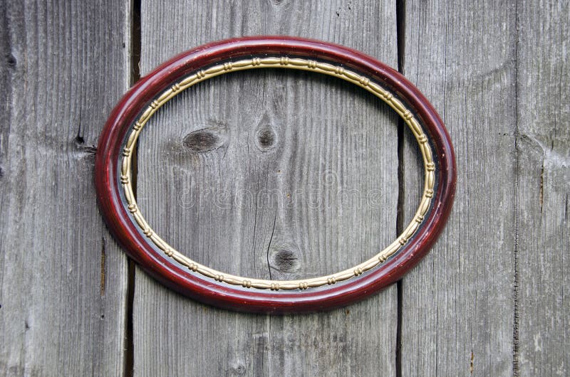 Old oval picture frame on ancient wooden wall