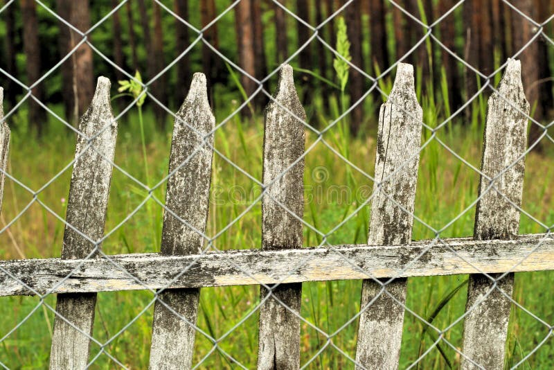 Old picket fence in the background of the chain-link fence. Vintage countryside landscape stock images