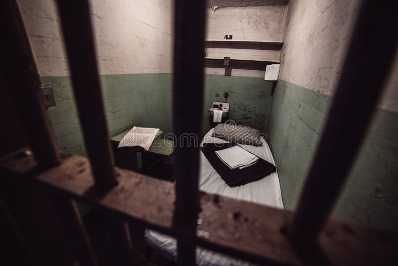 Old prison cell in prison jail with bed and restroom. Penitentiary system concept.