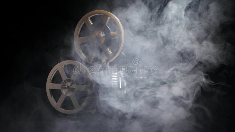 Old projector showing film in the smoke. Studio black background