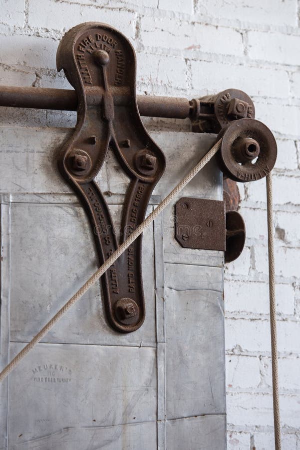Old pulley on metal sliding industrial door in old warehouse