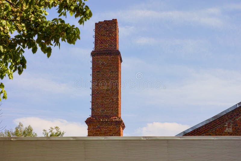 Old red brick chimney against blue sky stock image