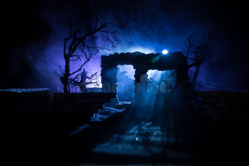 Old ruined stone house in deserted garden at night. Selective focus