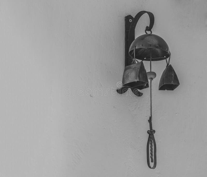 Old Rustic Warning Bell Cow Bell Hanging from the White Wall in Stock