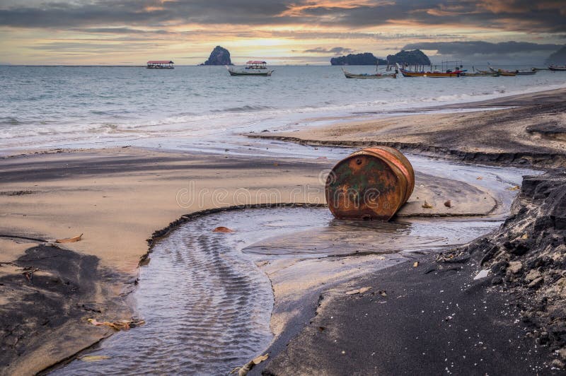 Old rusty barrel oil on beach in Asia on sunset