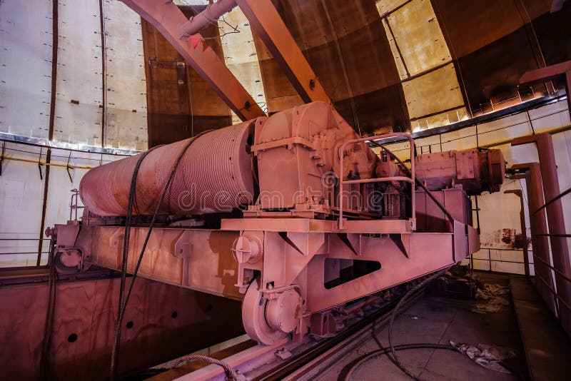 Old rusty industrial polar rotary crane of bridge type under dome of abandoned construction of power plant